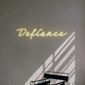 A yellow neon sign that says 'Defiance'