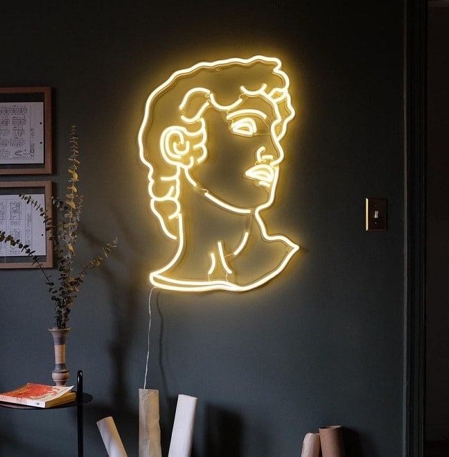 A yellow neon sign featuring a David's head motif hanging on a wall